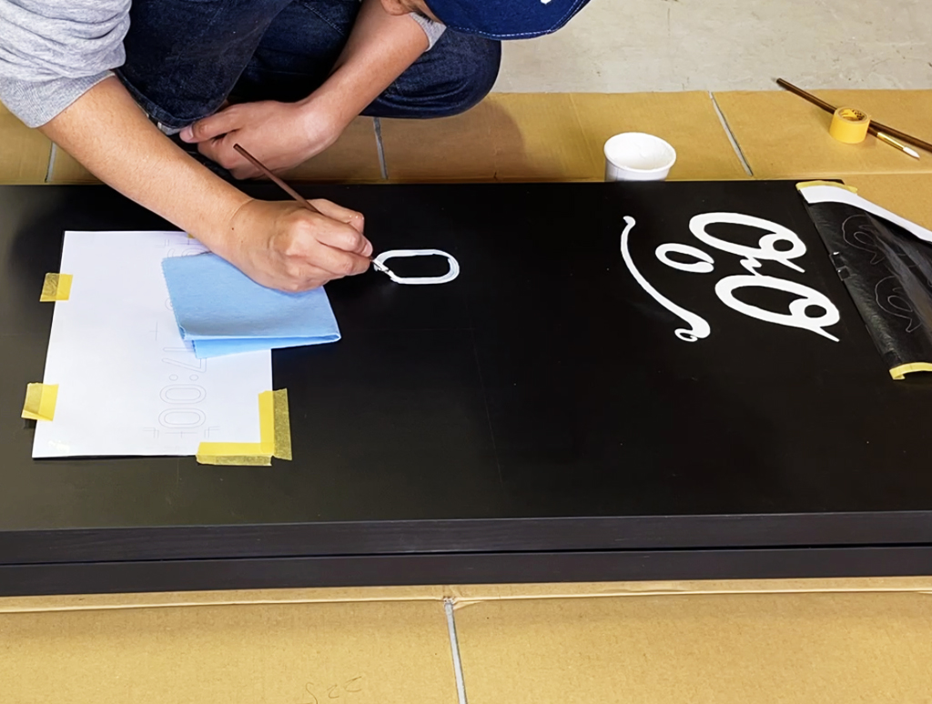 ONOONOの営業案内看板に白い文字を描く制作風景