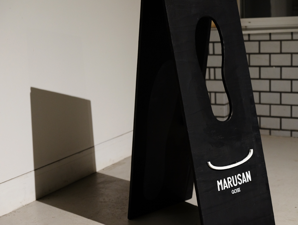 MARUSAN GOSEの看板に入れたロゴと壁に映る影