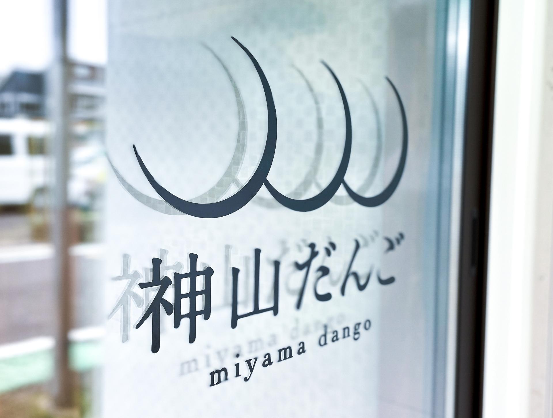 神山だんごのロゴを配したガラス面の店舗サイン