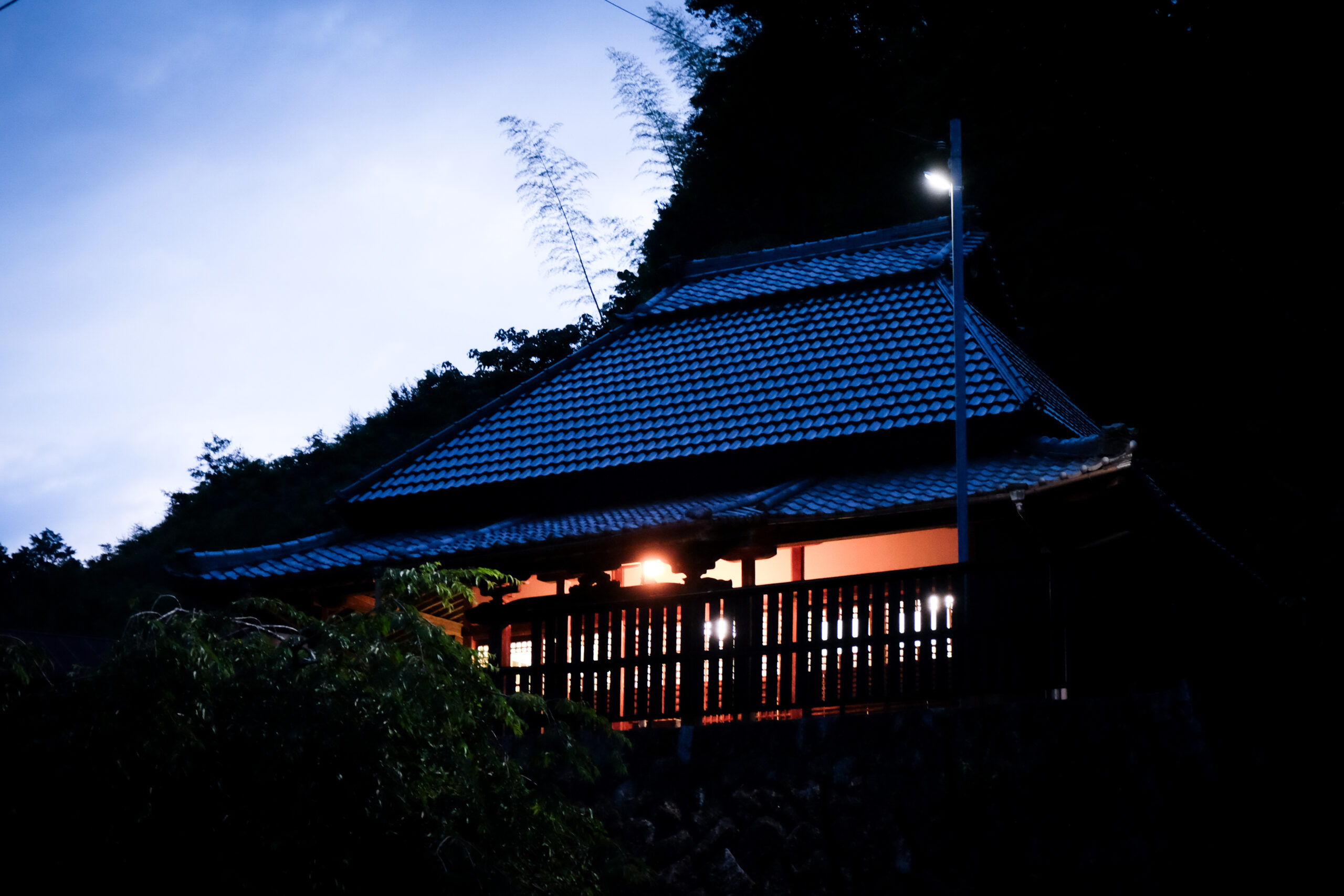 夕闇の中で明かりがともるお堂