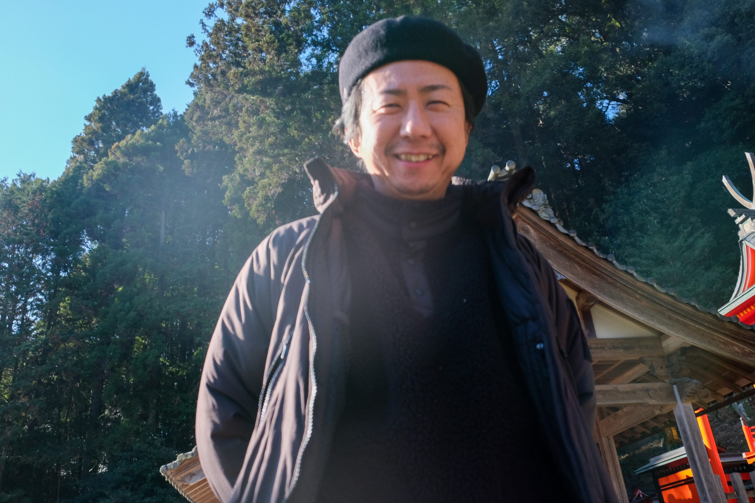 低い目線から見上げた笑顔の男性と神社の境内