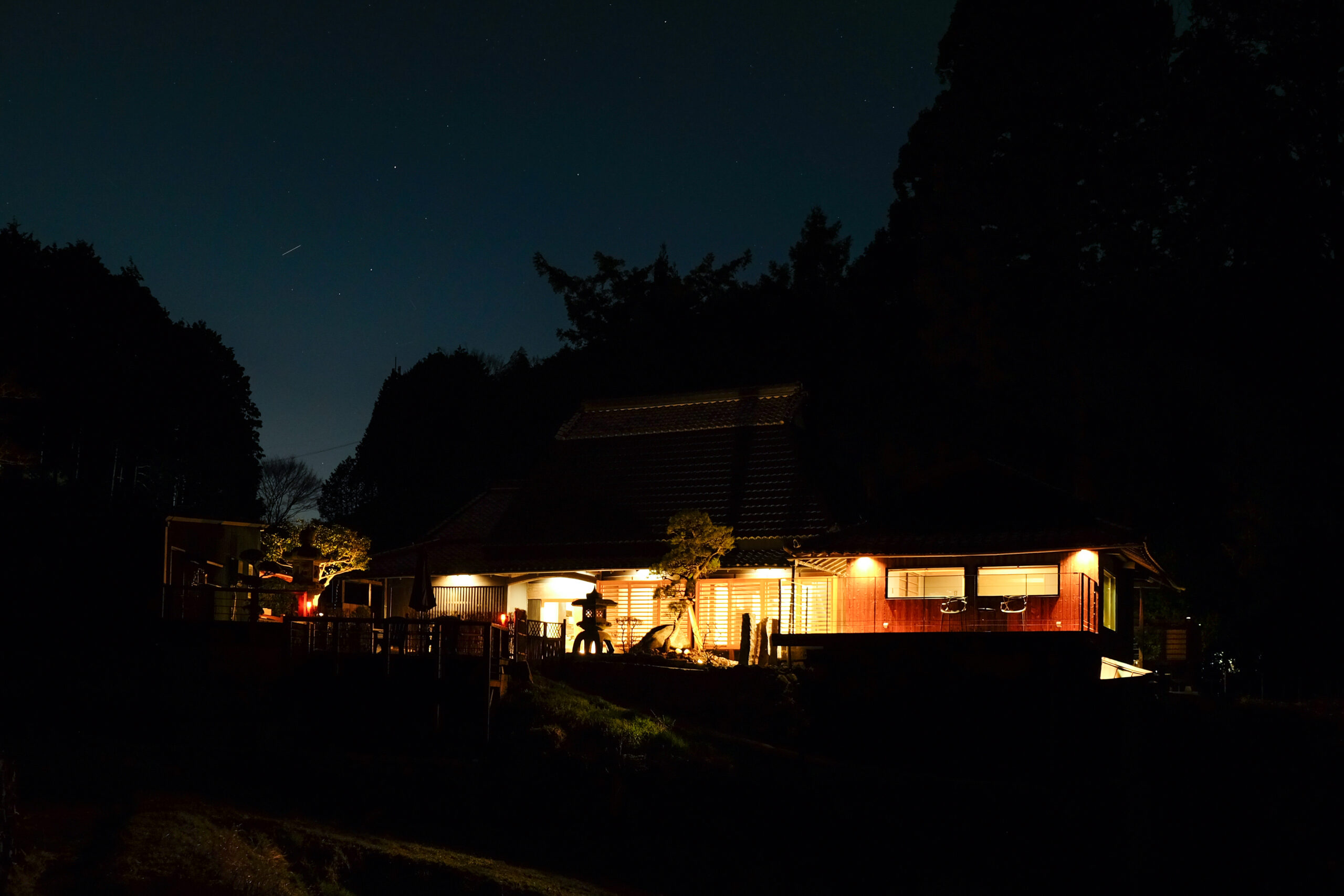夜の森を背に灯りがともる里音の外観